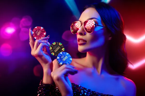 A woman smiling while playing online games on her laptop, surrounded by neon casino elements, showcasing SLO16’s diverse game collection.
